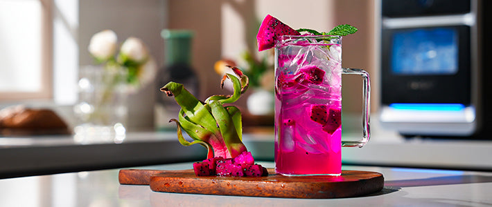 Dragon Fruit Mojito cocktail on a wooden board with dragon fruit garnish and mint leaves. Pink cocktail with ice and rum.