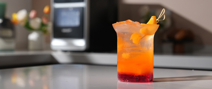 Yellow-peach Spark cocktail with layered orange and red hues, garnished with peach slices and ice.
